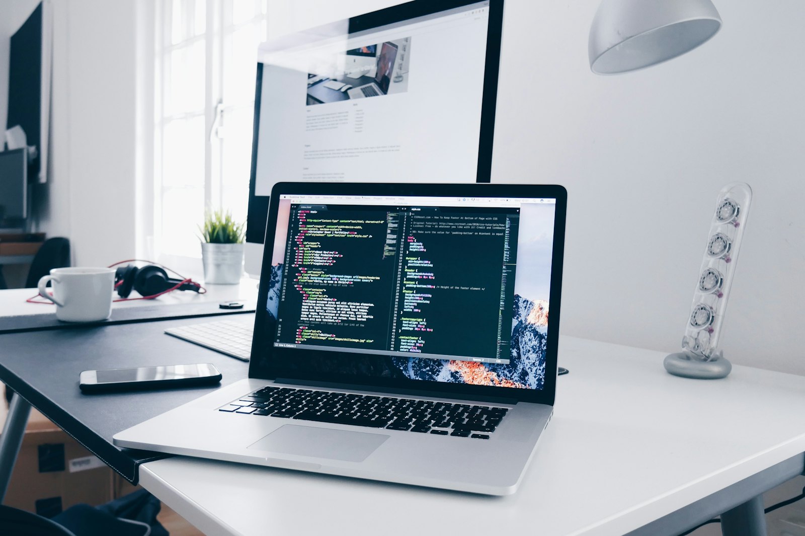 Laptop met een code-editor op een opgeruimd bureau waar een WordPress website wordt gebouwd
