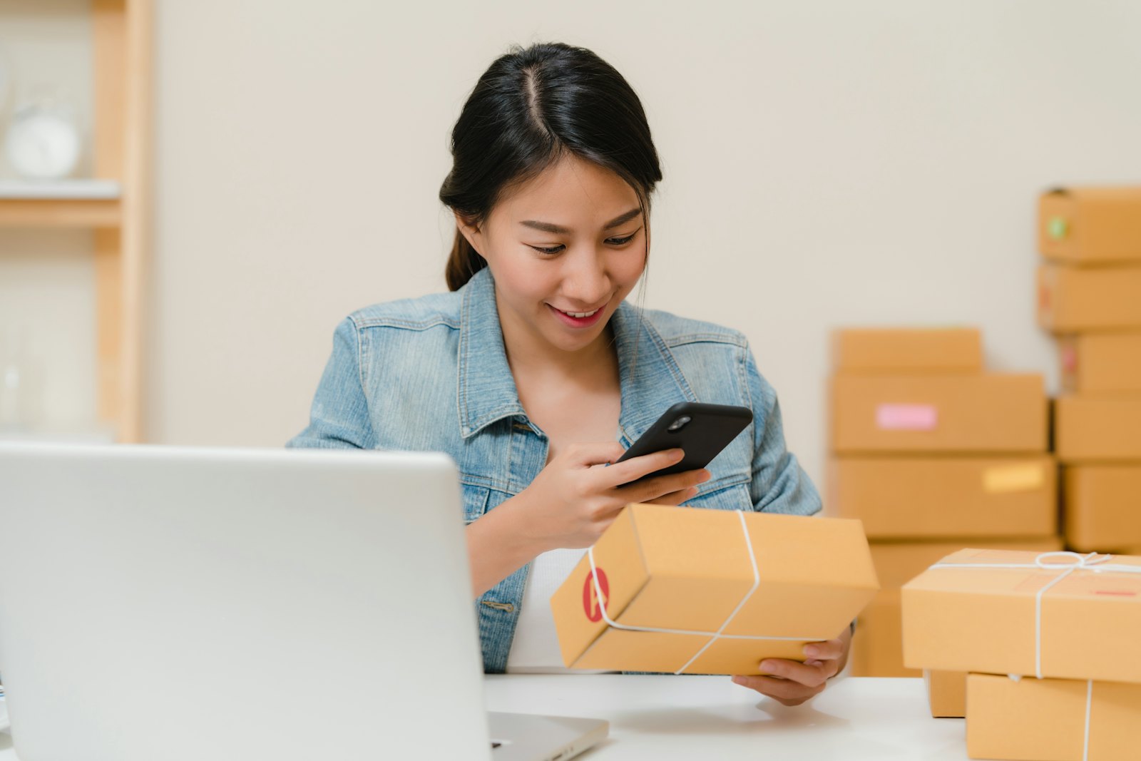 Kleine ondernemer pakt bestellingen van haar webshop in achter een laptop